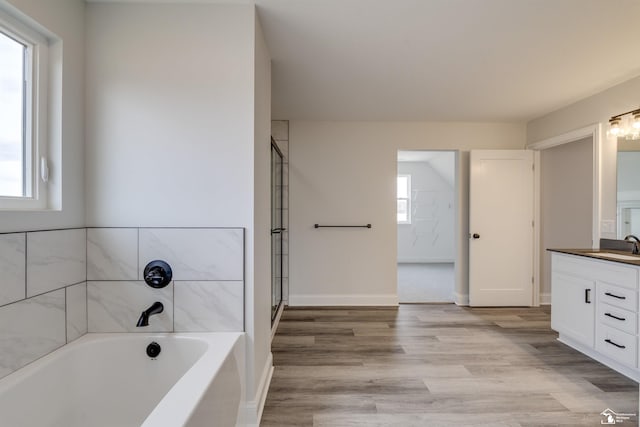 full bath featuring a garden tub, vanity, and wood finished floors