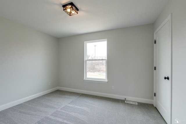 unfurnished room with carpet, visible vents, and baseboards