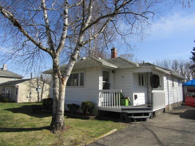 bungalow-style house with a front yard, a deck, and a chimney