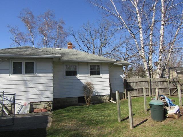 view of property exterior featuring a yard, fence, and a chimney