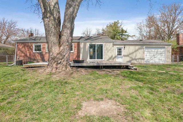 rear view of property featuring a chimney, fence, a garage, a lawn, and a deck