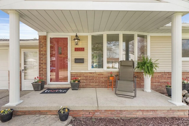 doorway to property with a porch and brick siding