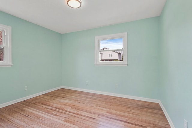 spare room featuring light wood-type flooring, a wealth of natural light, and baseboards