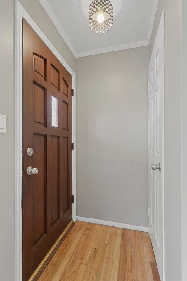 foyer entrance with light wood-type flooring, baseboards, and ornamental molding