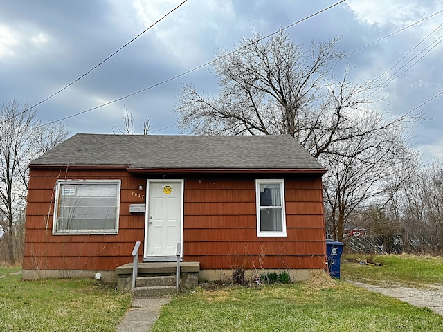 bungalow-style home with a front lawn and roof with shingles