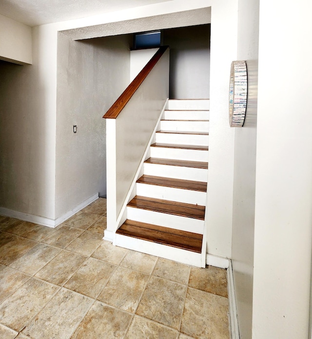 staircase with stone finish floor and baseboards