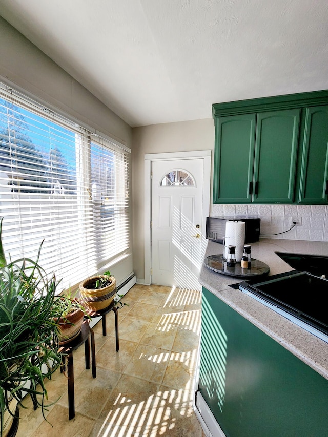kitchen with green cabinetry, a baseboard heating unit, and light countertops