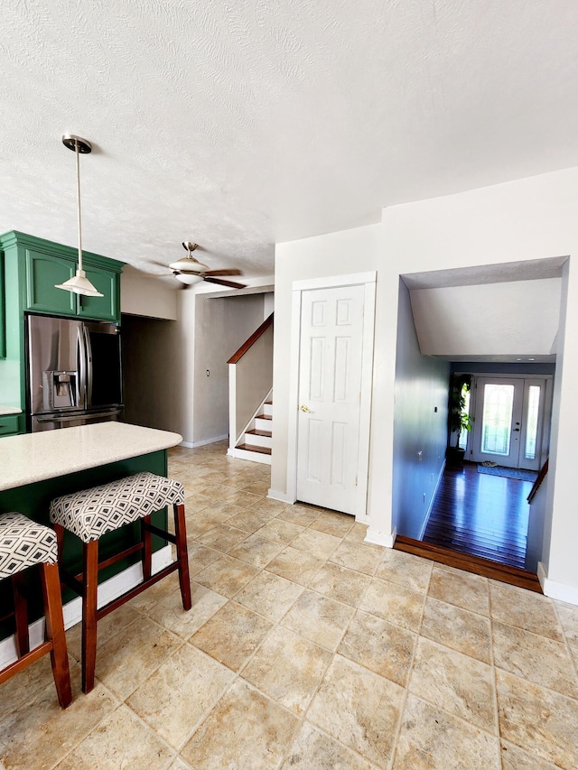 interior space with baseboards, light countertops, a ceiling fan, stainless steel refrigerator with ice dispenser, and green cabinetry