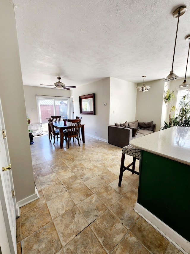 dining room with ceiling fan with notable chandelier, baseboards, and a textured ceiling