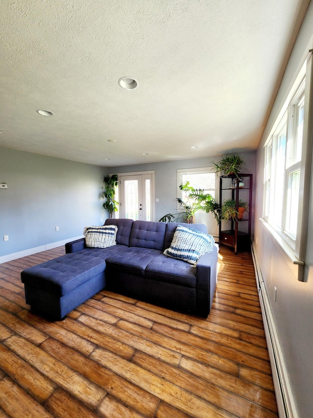 living area with baseboards, a baseboard radiator, a textured ceiling, recessed lighting, and hardwood / wood-style floors