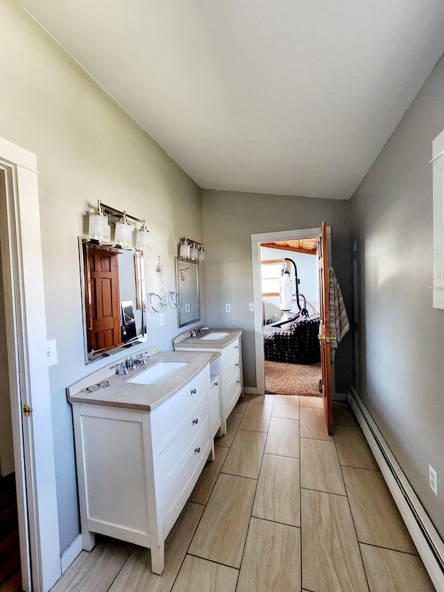 ensuite bathroom with ensuite bath, vanity, a baseboard radiator, and wood finished floors