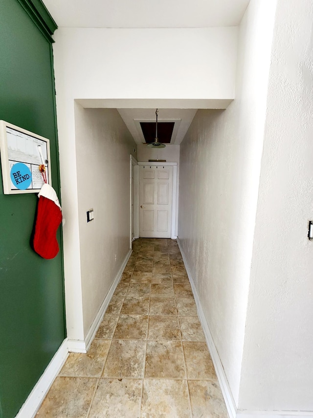 corridor featuring baseboards and stone finish floor