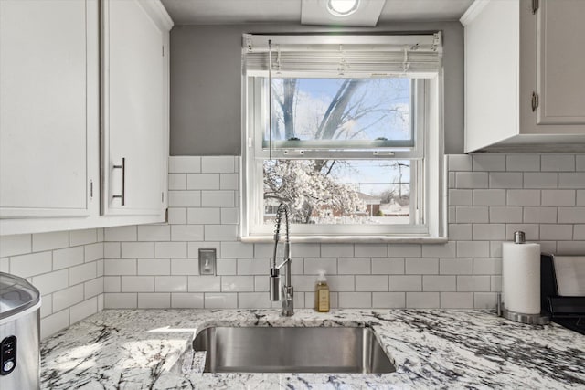 kitchen with white cabinetry, a sink, and backsplash