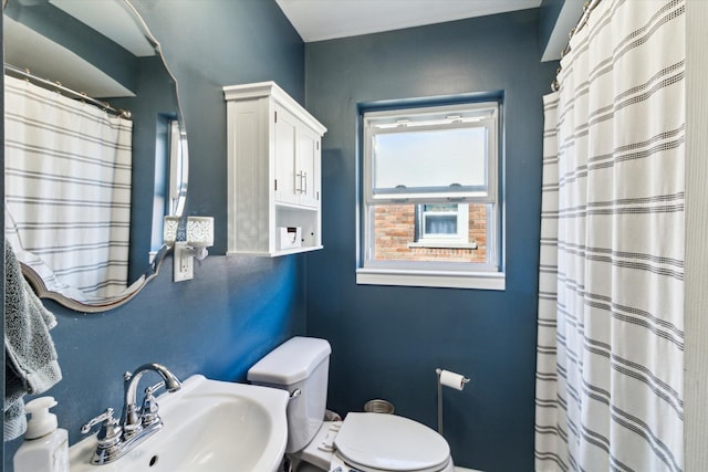 full bath with toilet, a shower with shower curtain, and a sink