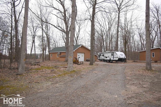 view of front facade featuring a detached garage and dirt driveway