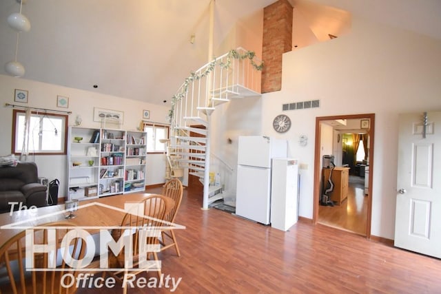 dining area with wood finished floors, a healthy amount of sunlight, visible vents, and stairs