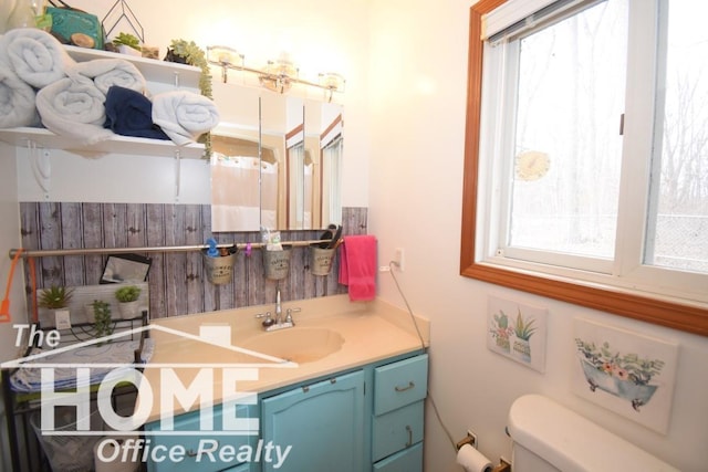 half bath featuring vanity, toilet, and a healthy amount of sunlight