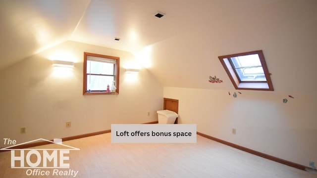 additional living space featuring vaulted ceiling with skylight and baseboards