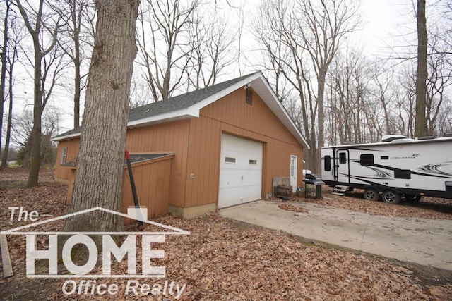 view of side of home with concrete driveway, an outbuilding, and a detached garage