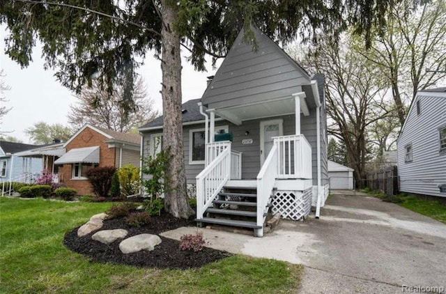 23737 Couzens Ave, Hazel Park, MI 48030 - view of front of house with a front yard, a detached garage, an outdoor structure, and covered porch