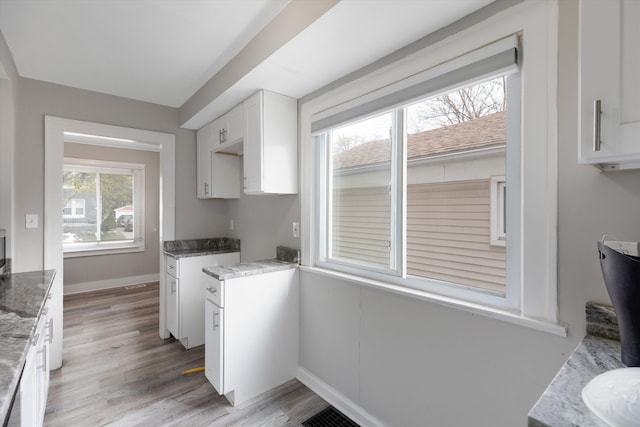 23737 Couzens Ave, Hazel Park, MI 48030 - kitchen with light stone counters, light wood-style flooring, baseboards, white cabinetry, and visible vents