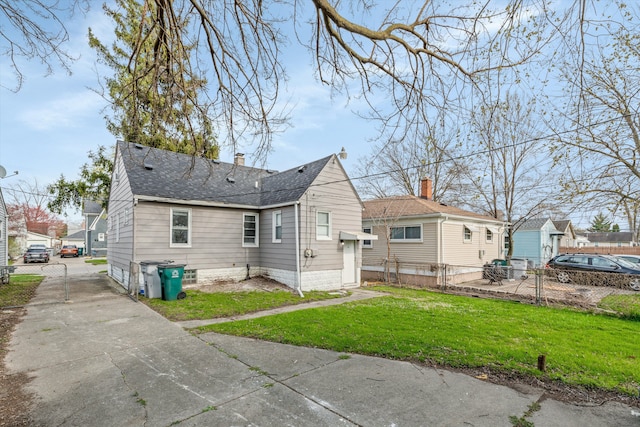 23737 Couzens Ave, Hazel Park, MI 48030 - back of property featuring a chimney, driveway, fence, a yard, and roof with shingles