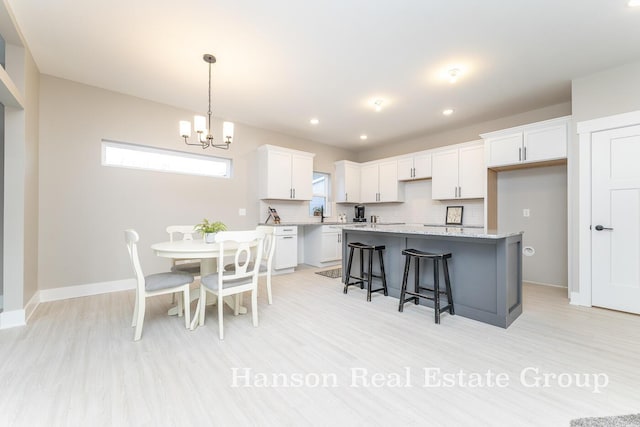 kitchen featuring an inviting chandelier, light wood-style flooring, tasteful backsplash, white cabinetry, and a center island