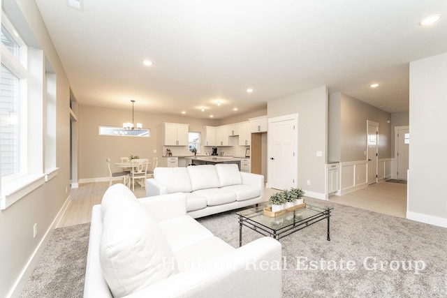 living room featuring light colored carpet, recessed lighting, and a notable chandelier