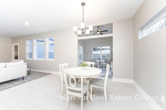 dining room with light wood finished floors, baseboards, and ceiling fan with notable chandelier
