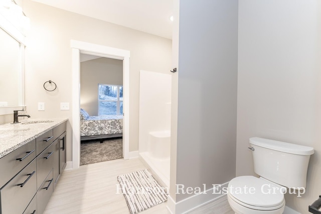 ensuite bathroom with ensuite bathroom, vanity, toilet, wood finished floors, and walk in shower
