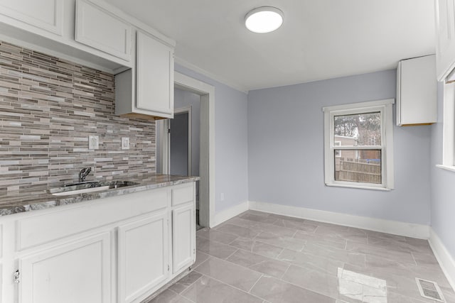 1409 Charter St, Lincoln Park, MI 48146 - kitchen with white cabinets, visible vents, a sink, baseboards, and backsplash