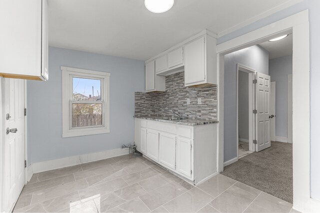 1409 Charter St, Lincoln Park, MI 48146 - kitchen featuring stone counters, white cabinetry, a sink, decorative backsplash, and baseboards