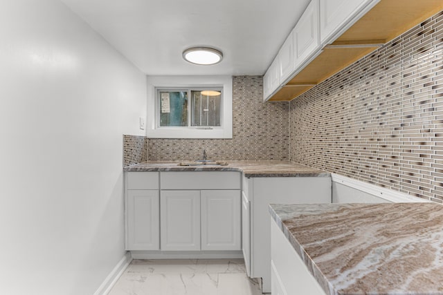 1409 Charter St, Lincoln Park, MI 48146 - kitchen with marble finish floor, a sink, backsplash, and white cabinets