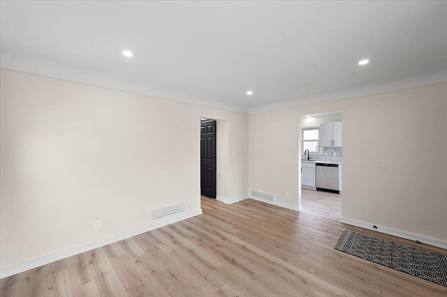 spare room with light wood-type flooring, visible vents, recessed lighting, a sink, and baseboards