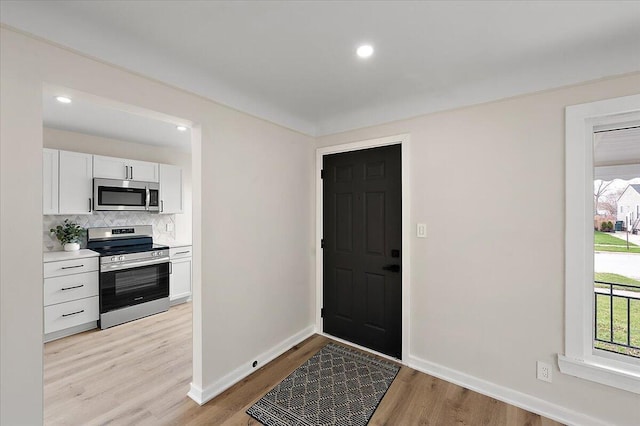foyer with light wood-style flooring, baseboards, and recessed lighting
