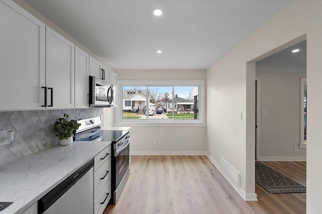 kitchen with tasteful backsplash, light wood-type flooring, appliances with stainless steel finishes, and visible vents