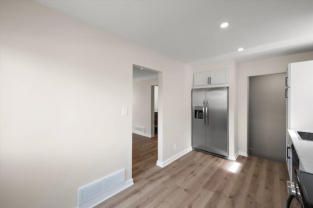 kitchen with white cabinets, recessed lighting, visible vents, light wood-style floors, and stainless steel fridge