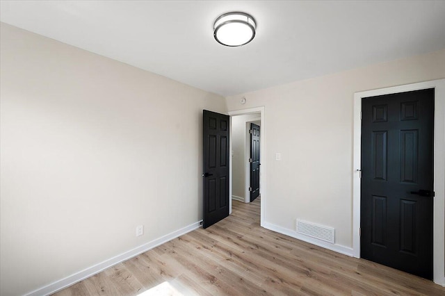 unfurnished bedroom with light wood-style flooring, visible vents, and baseboards