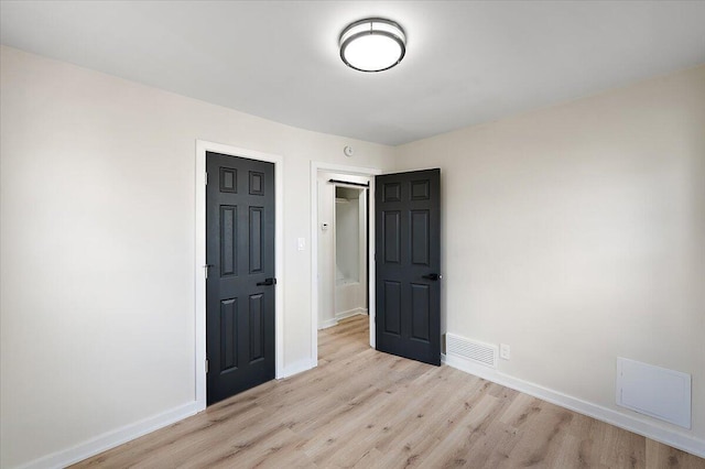 unfurnished bedroom with light wood finished floors, baseboards, and visible vents