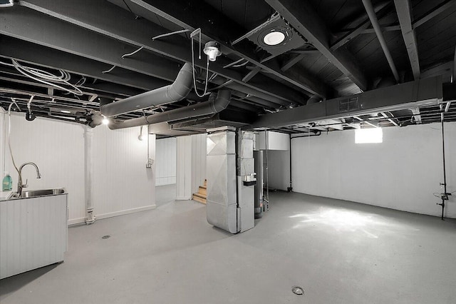 basement featuring a sink, water heater, and heating unit