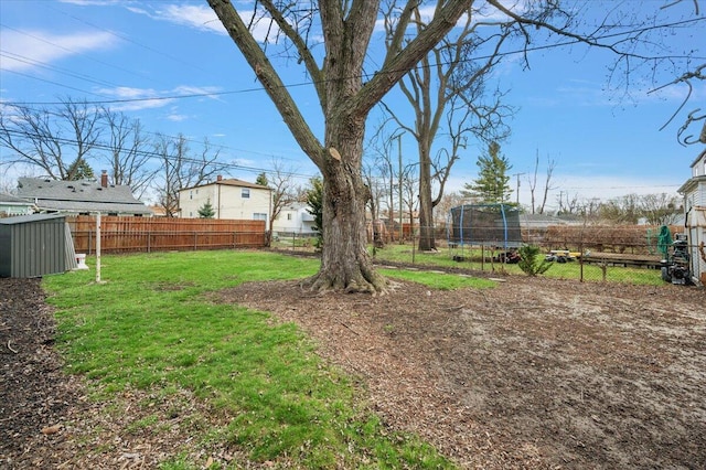 view of yard featuring an outdoor structure, a trampoline, a shed, and a fenced backyard