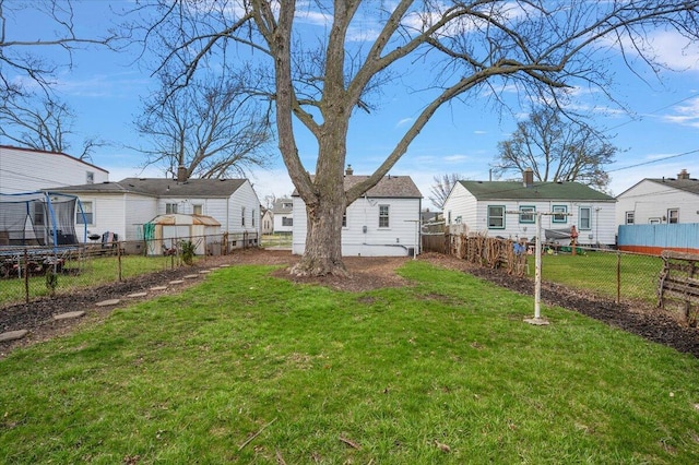 view of yard featuring a trampoline, a fenced backyard, a residential view, and an outdoor structure