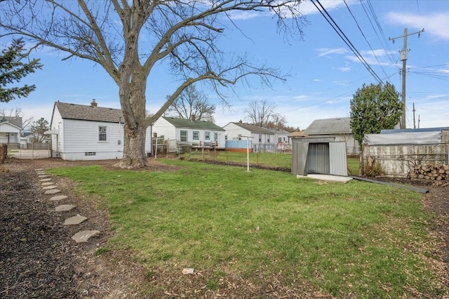 view of yard with a storage unit, an outbuilding, and fence