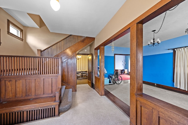 hall featuring carpet floors, stairs, and an inviting chandelier