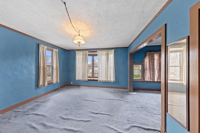 unfurnished room featuring carpet floors, a textured ceiling, crown molding, and baseboards