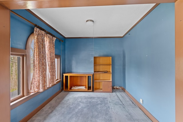 unfurnished dining area with crown molding, carpet flooring, and baseboards