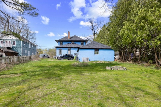 back of property featuring a yard, a chimney, and fence