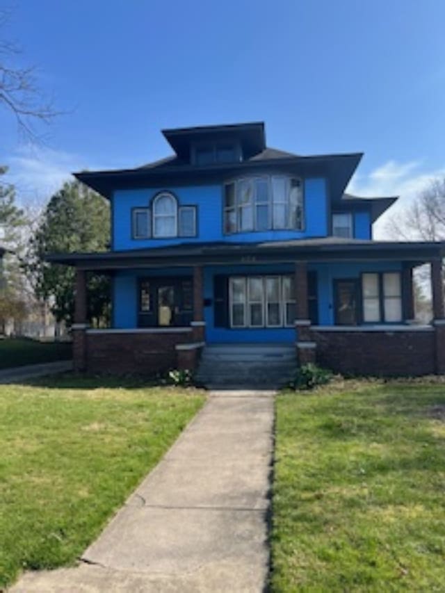 american foursquare style home with a front lawn and a porch