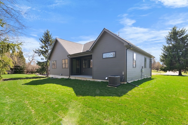back of house with central air condition unit and a lawn