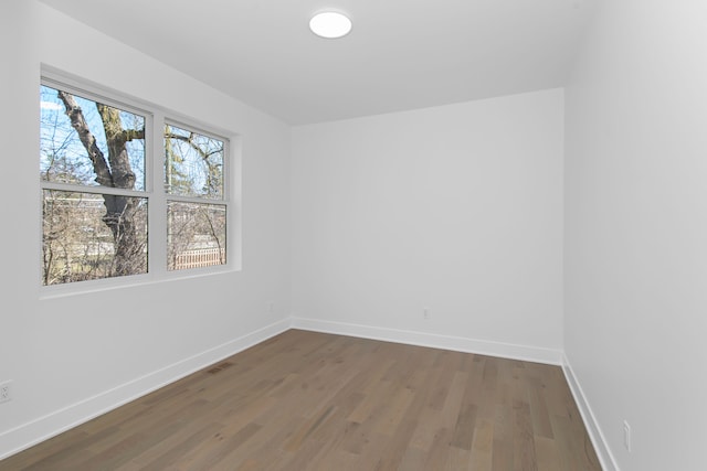 spare room featuring baseboards, wood finished floors, and visible vents